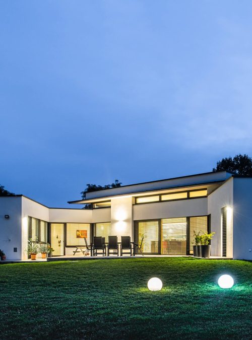 Rückansicht des Hauses mit Gartenbeleuchtung und einer gemütlichen Terrasse am Abend