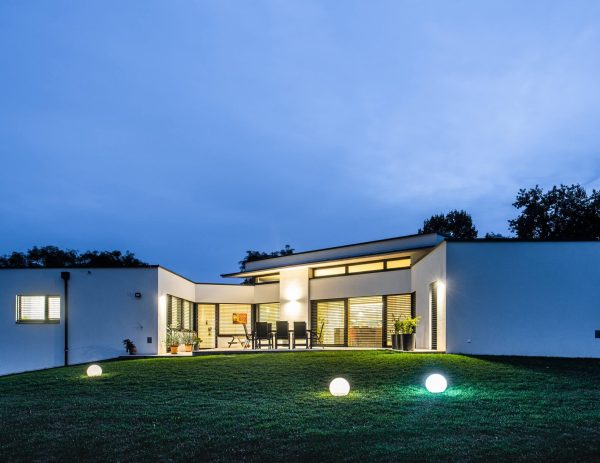Rückansicht des Hauses mit Gartenbeleuchtung und einer gemütlichen Terrasse am Abend